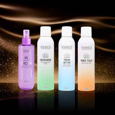 Four VODUZ hair care products on a reflective surface with a dark, swirling background.