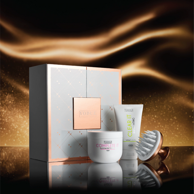 Voduz Reset Vault hair care set with products and packaging on a reflective surface with a warm glow.