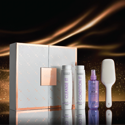 Voduz Shine Vault hair care product set with bottles, a spray bottle, and a brush on a reflective surface with a dark background.