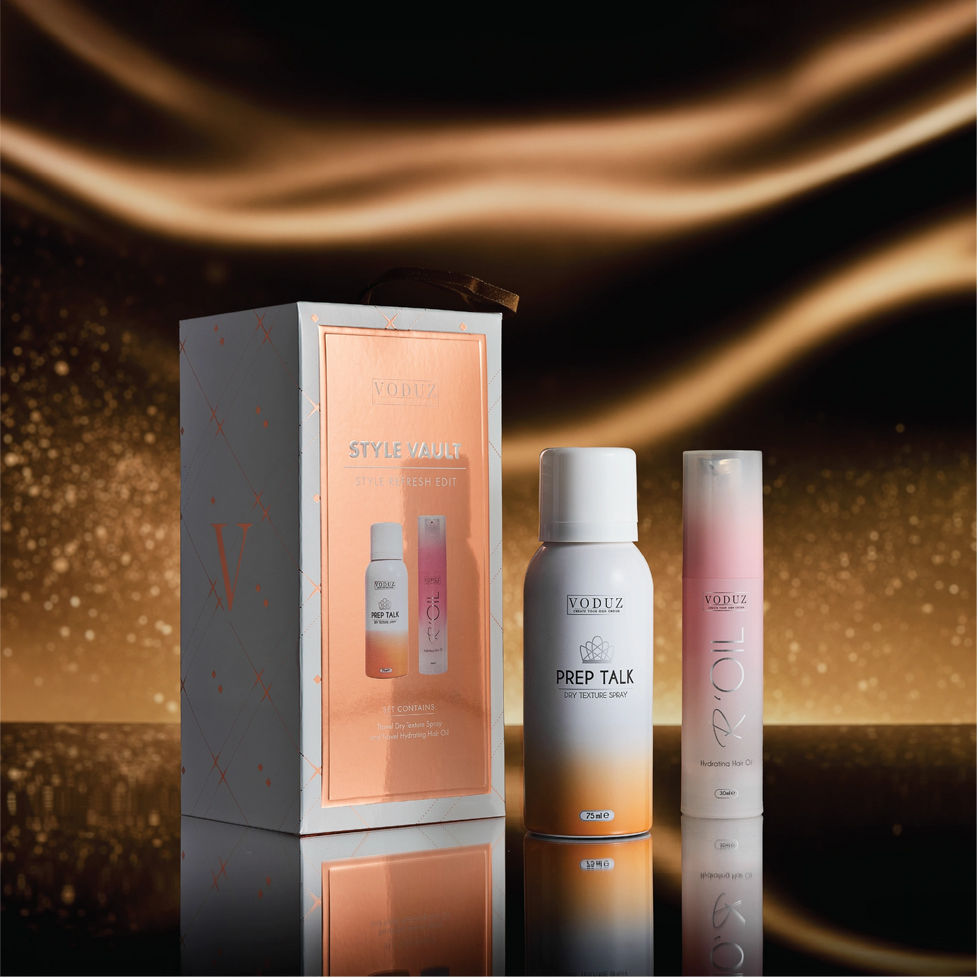 Voduz Style Vault hair care products including a box, two bottles, and a spray can on a reflective surface with a warm glow.