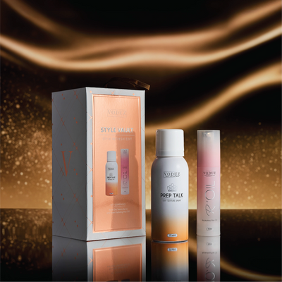 Voduz Style Vault hair care products including a box, two bottles, and a spray can on a reflective surface with a warm glow.