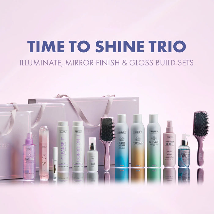 A hair care gift set featuring multiple VODUZ skincare bottles and brushes arranged in front of two white gift bags on a soft pink gradient background with the text 'TIME TO SHINE TRIO'.