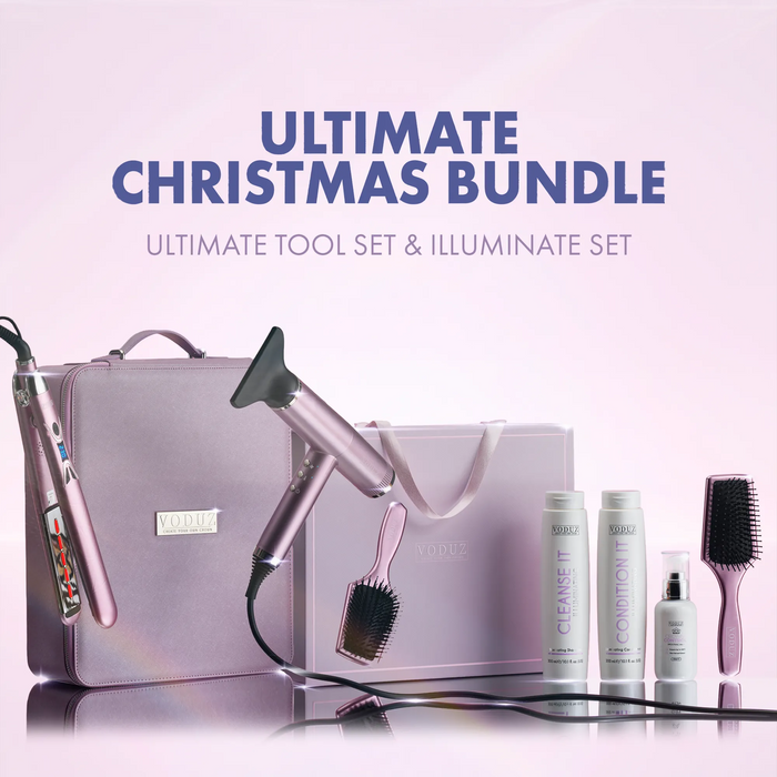 Voduz Ultimate Christmas Bundle featuring a pink travel case, Blow Out Pro hair dryer, Legacy Interred Straightener, brush, and three hair care bottles on a reflective light pink background with promotional text.